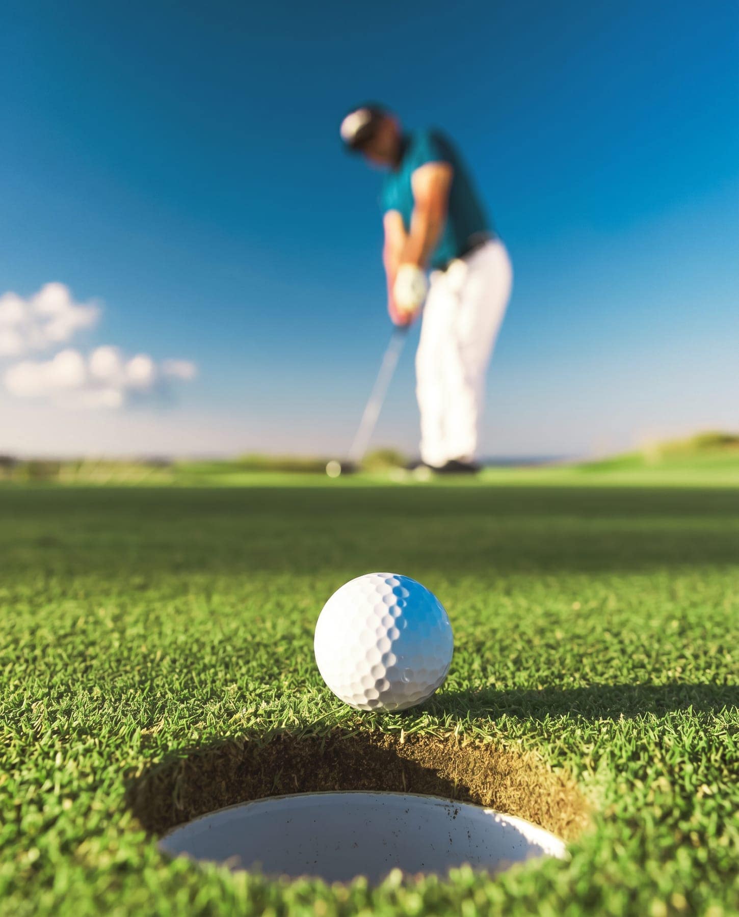 A golfer putting, the ball at the lip of the hole