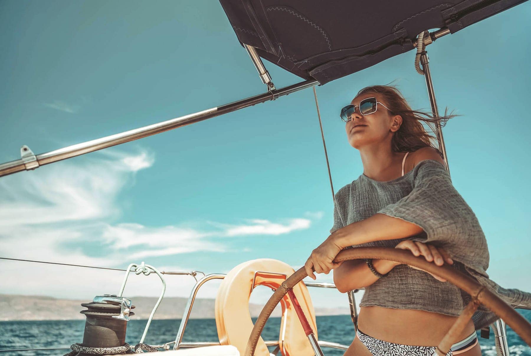 A woman at the helm of a yacht under sail