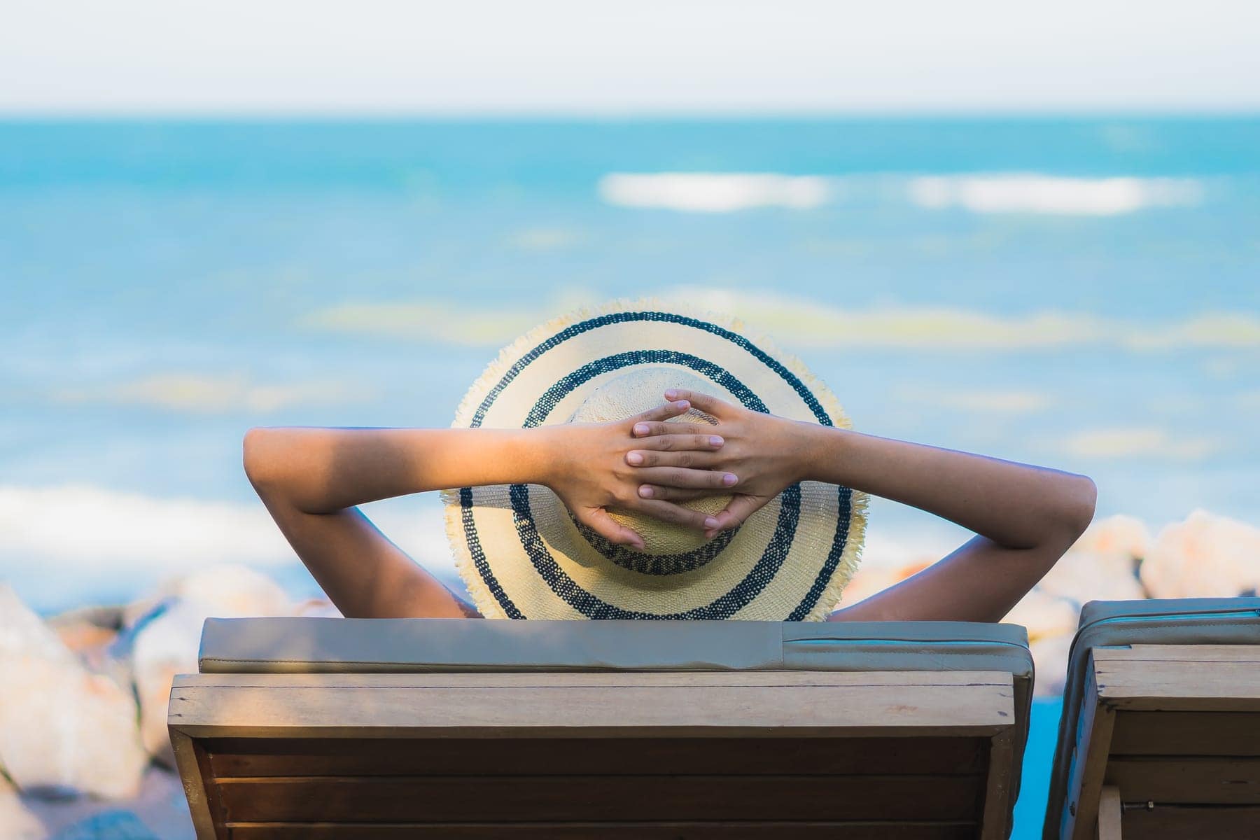 A woman in a sun hat relaxing on a lounger by the sea