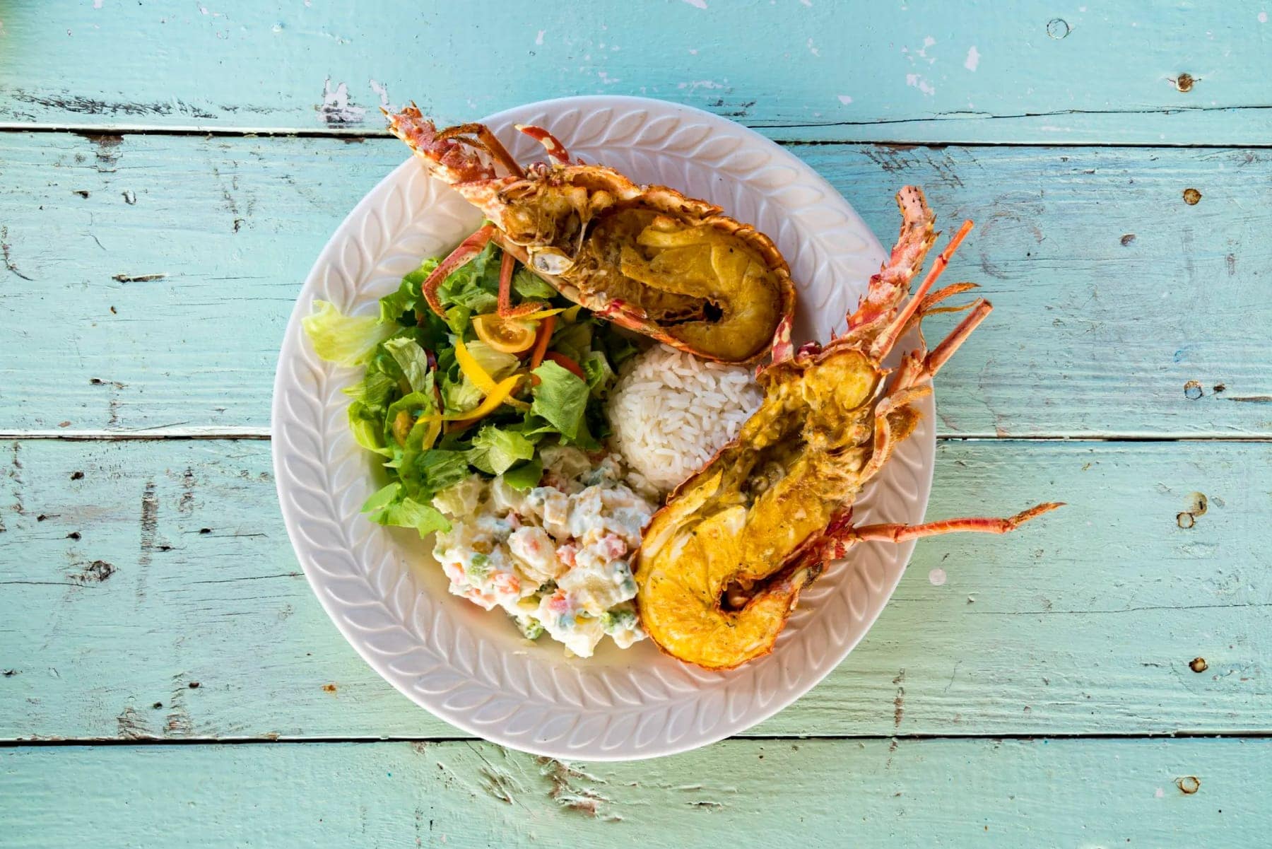 Grilled lobster and salad on a turquoise table